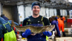 Barry-Reid-skipper-of-the-Audacious-BF83-holds-a-North-Sea-cod-in-Peterhead-fish-market-credit-MSC-Eleanor-Church