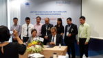 Truong Thi Le Khanh and Morten Nordstad sign their deal, watched by representatives of the Vietnamese government